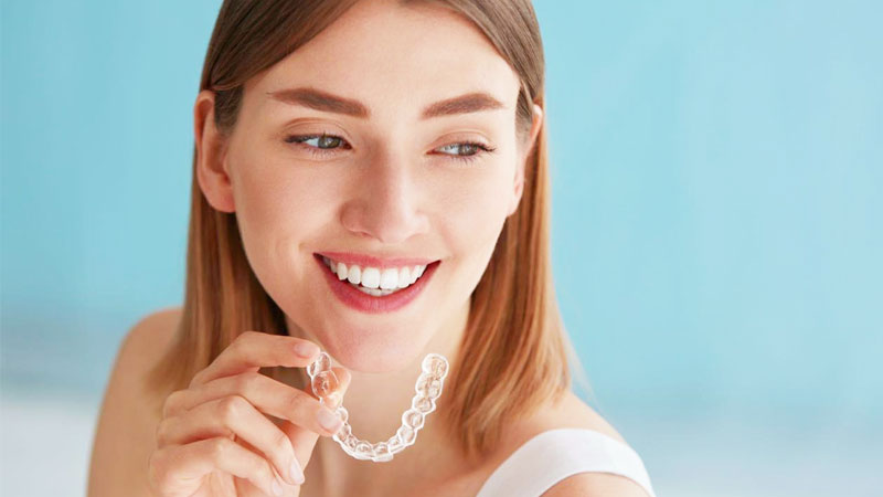 Una ragazza tiene in mano una mascherina trasparente Invisalign